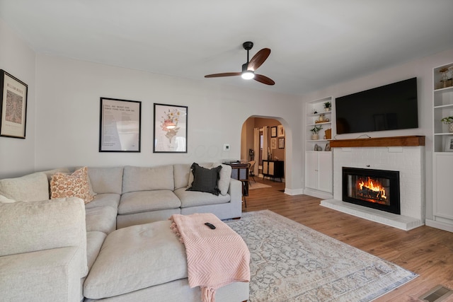 living room featuring ceiling fan, a fireplace, and light hardwood / wood-style floors