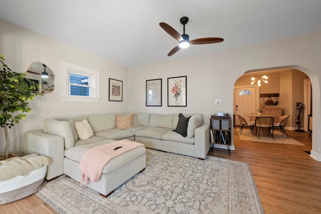 living room featuring ceiling fan with notable chandelier and light wood-type flooring