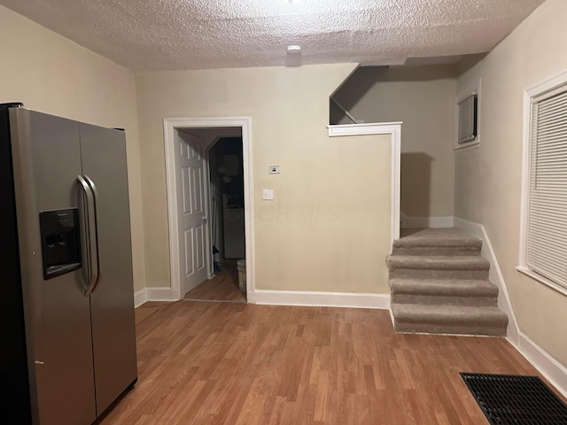 interior space with stainless steel fridge, light hardwood / wood-style floors, and a textured ceiling