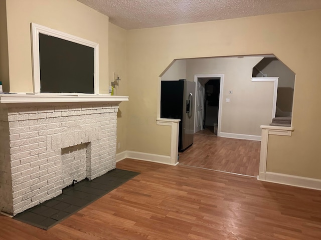 unfurnished living room featuring hardwood / wood-style floors, a fireplace, and a textured ceiling