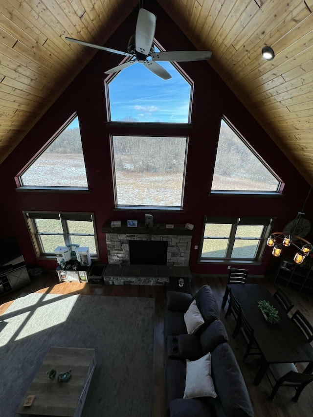 living area featuring ceiling fan, high vaulted ceiling, a stone fireplace, and wood ceiling