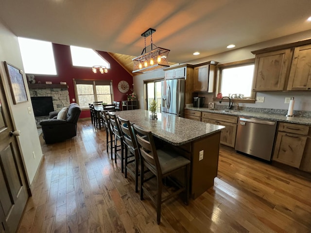 kitchen with a breakfast bar, lofted ceiling, sink, a center island, and stainless steel appliances