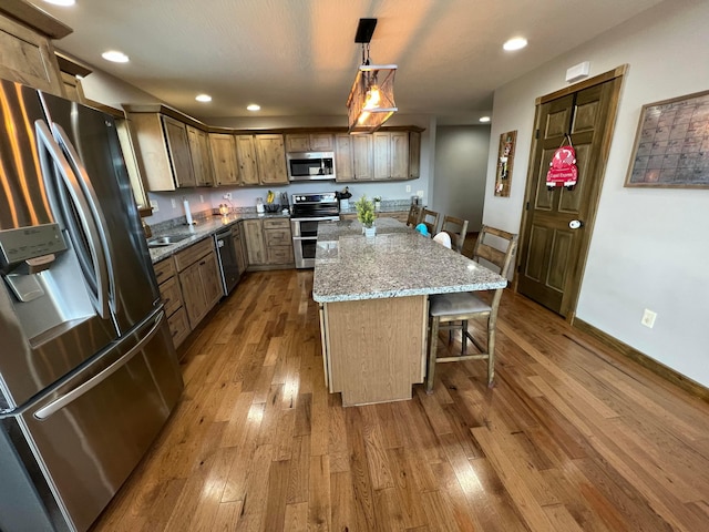 kitchen featuring hardwood / wood-style flooring, a kitchen island, a kitchen bar, and appliances with stainless steel finishes