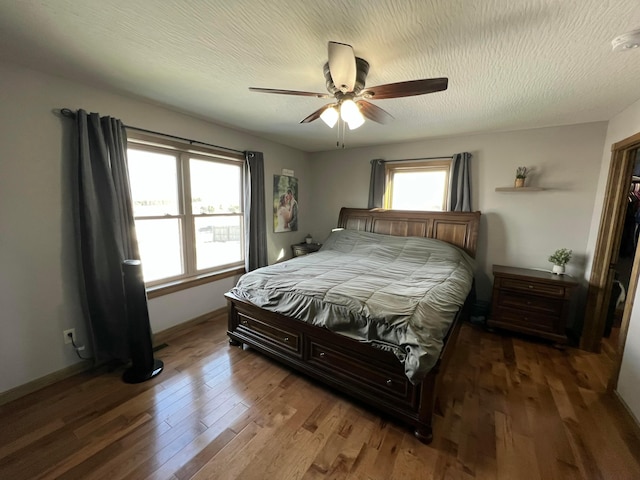 bedroom with ceiling fan, a textured ceiling, baseboards, and wood finished floors