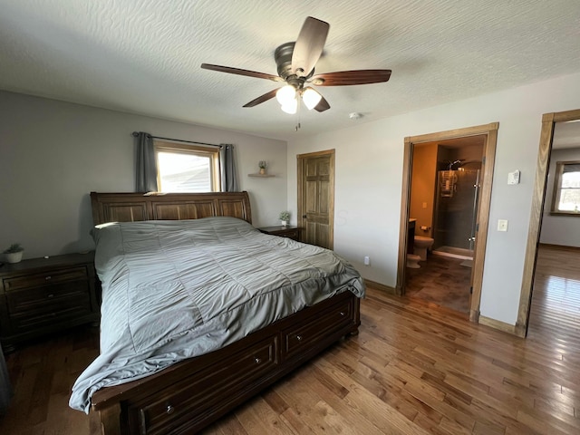 bedroom featuring a textured ceiling, multiple windows, wood finished floors, and baseboards