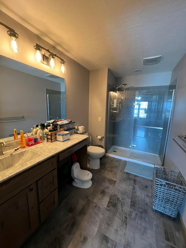 bathroom with vanity, tiled shower, and toilet