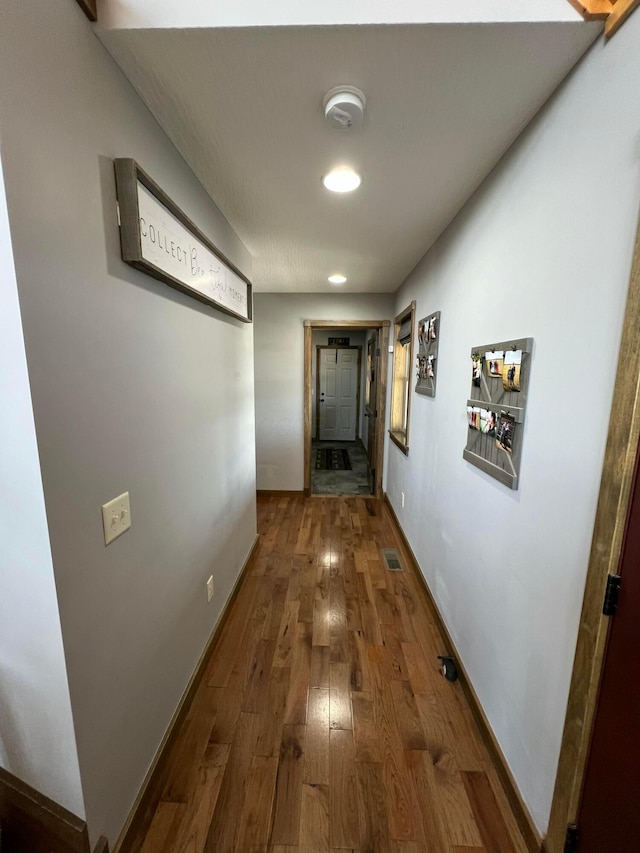 corridor with visible vents, baseboards, and wood finished floors