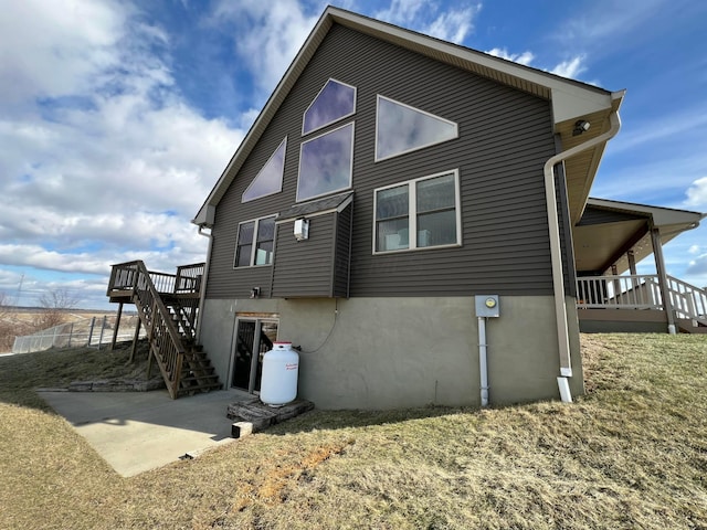 view of side of home featuring stairs, a patio, a deck, and stucco siding