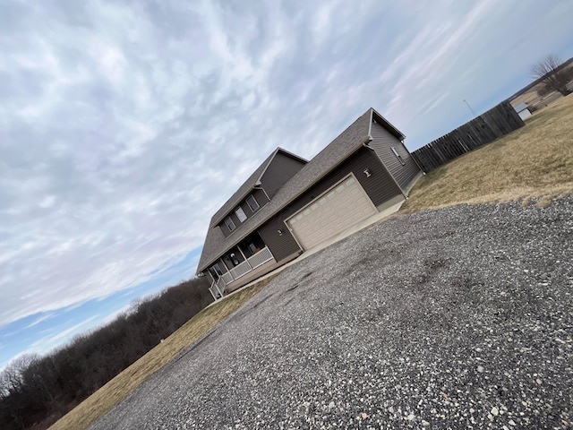 details with gravel driveway, a flat roof, and fence