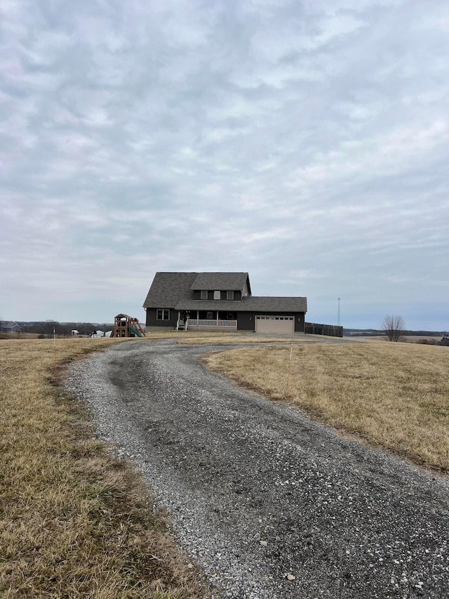 view of front of property with roof with shingles, an attached garage, and gravel driveway