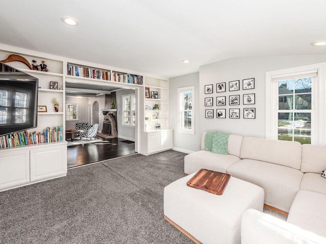 living room featuring vaulted ceiling, a healthy amount of sunlight, and dark colored carpet