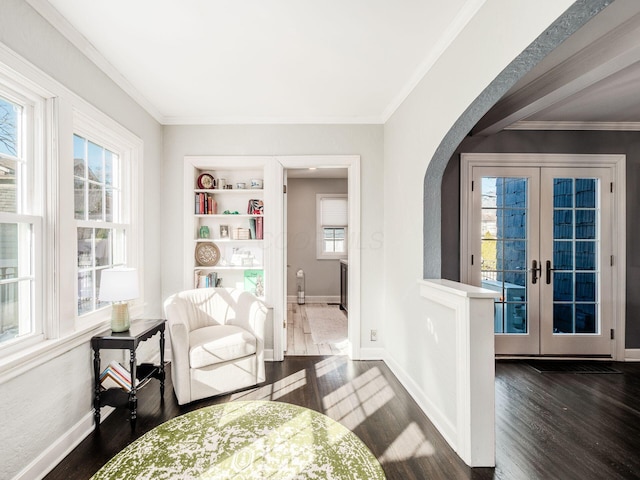 living area with french doors, dark hardwood / wood-style floors, crown molding, and built in shelves