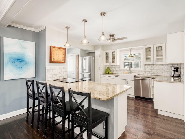 kitchen with a breakfast bar, pendant lighting, sink, white cabinets, and stainless steel appliances