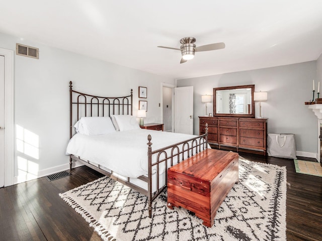 bedroom featuring dark hardwood / wood-style flooring, a fireplace, and ceiling fan