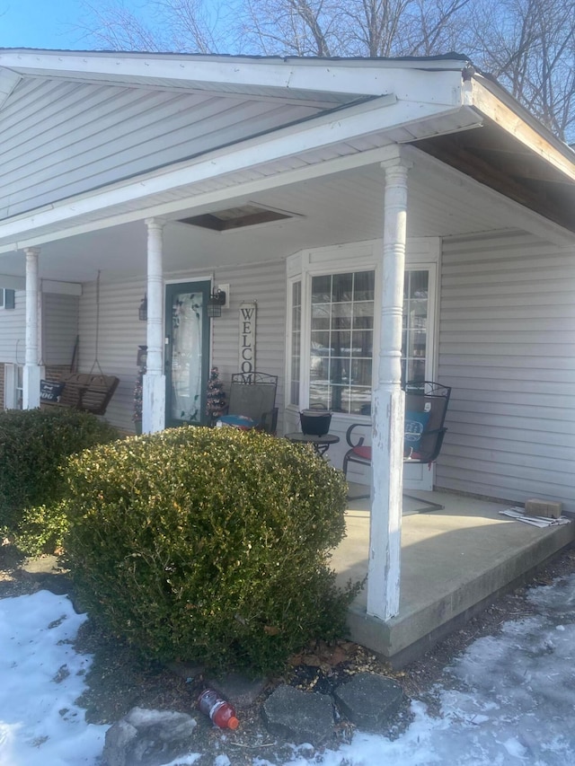 snow covered property entrance featuring a porch