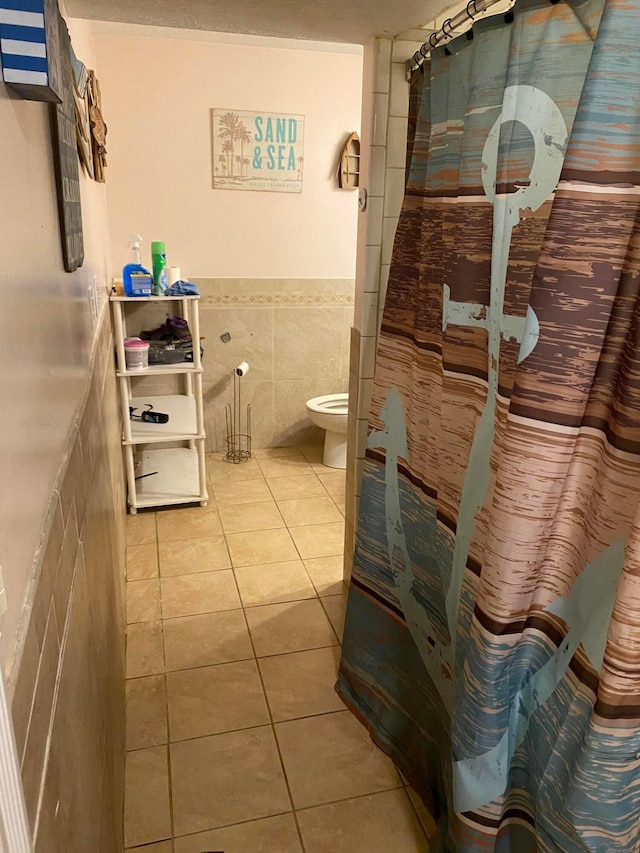 bathroom with tile patterned floors, toilet, and tile walls