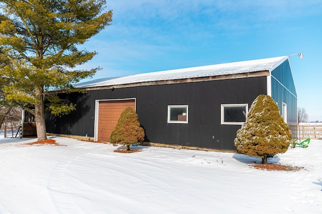 view of snow covered exterior with a garage and an outbuilding