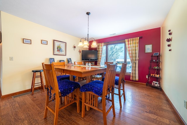 dining room with dark hardwood / wood-style flooring and a notable chandelier