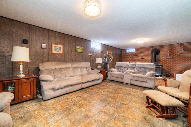 living room with a textured ceiling, wooden walls, brick wall, and a wood stove