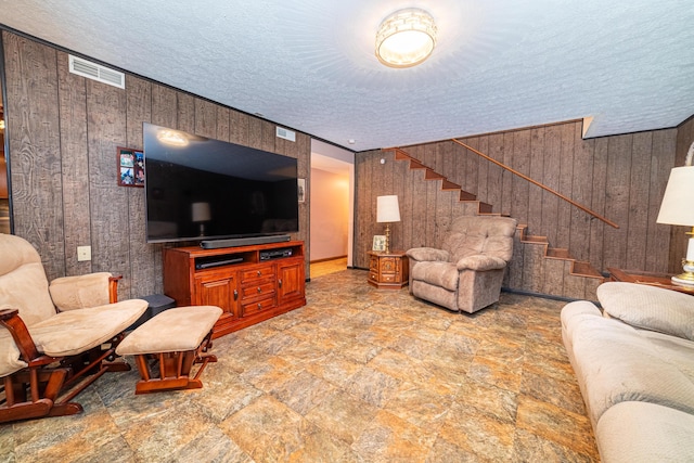 living room featuring a textured ceiling and wood walls