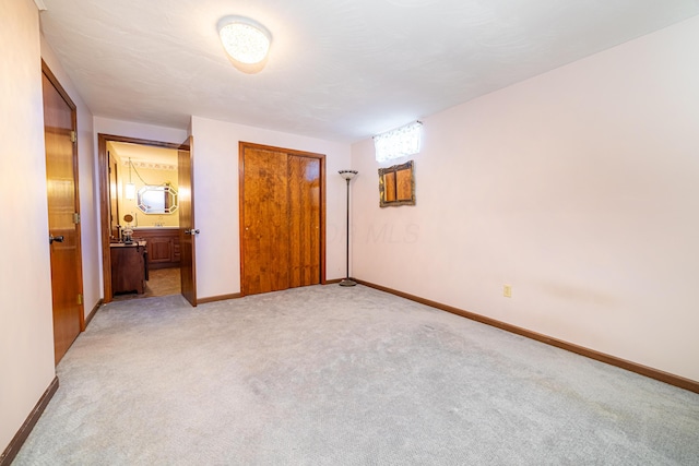 unfurnished bedroom with light colored carpet and ensuite bathroom