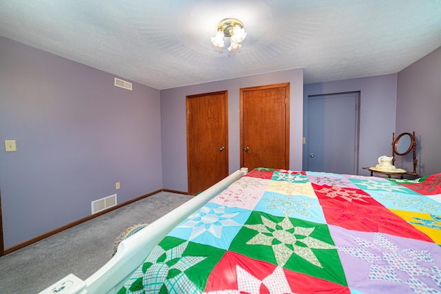 unfurnished bedroom featuring two closets, carpet floors, and a textured ceiling