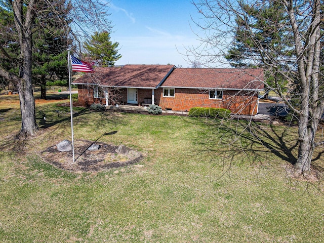 rear view of property with roof with shingles, a yard, covered porch, crawl space, and brick siding
