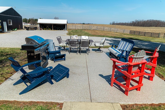 view of patio featuring area for grilling, a rural view, an outdoor structure, and fence