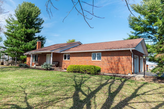 back of property featuring an attached garage, a lawn, brick siding, and a chimney