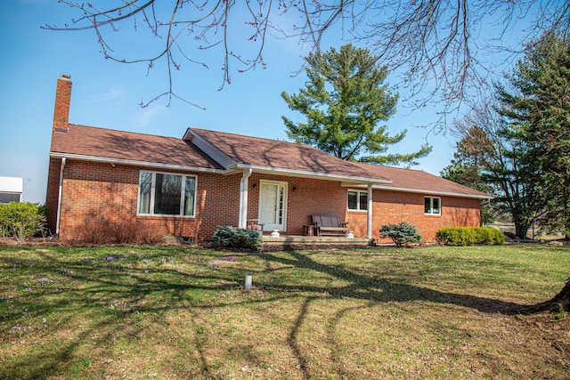 back of property with a lawn, brick siding, and a chimney