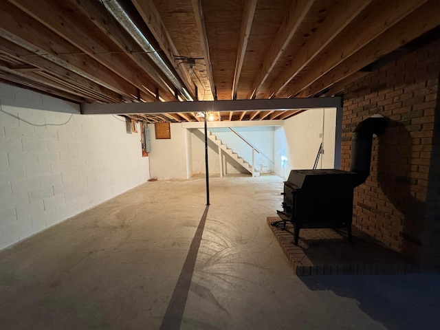 basement with a wood stove and electric panel