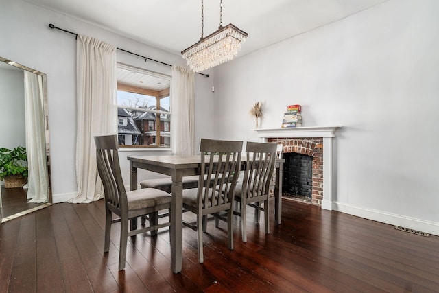 dining space with a fireplace, dark hardwood / wood-style floors, and a chandelier