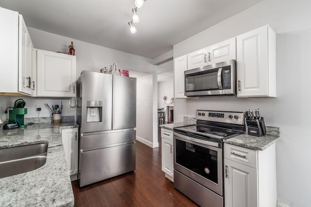 kitchen featuring white cabinetry, stainless steel appliances, dark hardwood / wood-style flooring, and light stone countertops