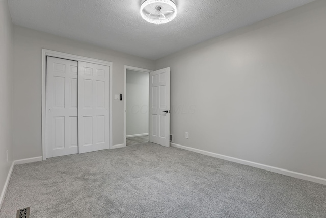 unfurnished bedroom featuring carpet floors, a textured ceiling, and a closet