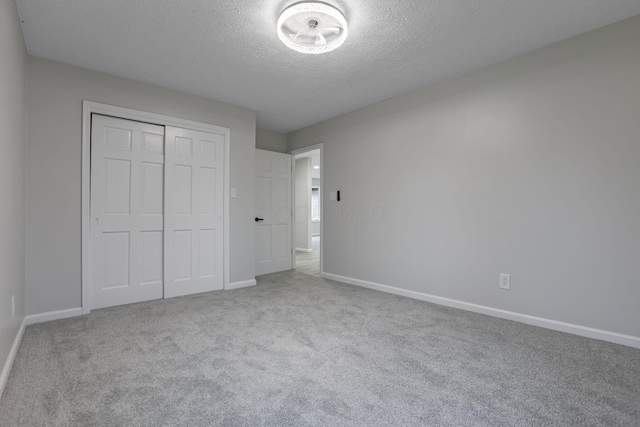 unfurnished bedroom featuring light colored carpet, a closet, and a textured ceiling