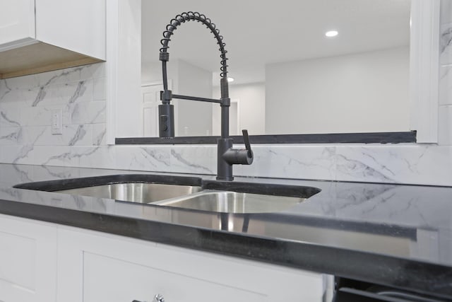 interior details with backsplash, sink, and white cabinets