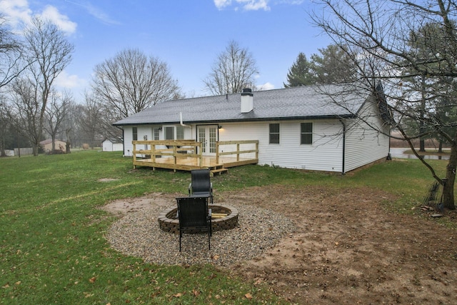 rear view of house featuring a wooden deck, an outdoor fire pit, and a lawn