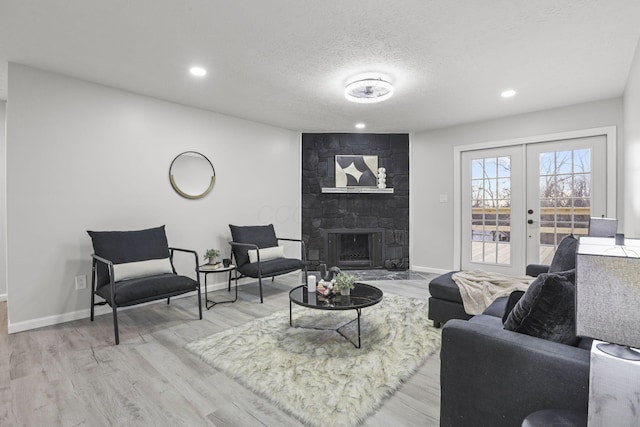 living room with wood-type flooring, a fireplace, a textured ceiling, and french doors