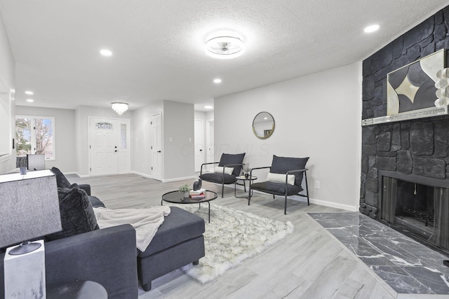 living room featuring a fireplace, light hardwood / wood-style floors, and a textured ceiling