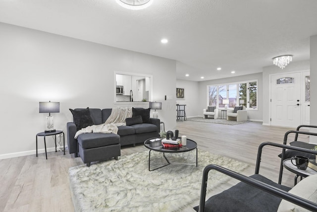 living room with a chandelier, sink, light hardwood / wood-style flooring, and a textured ceiling