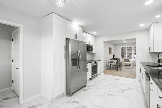 kitchen with appliances with stainless steel finishes, sink, a textured ceiling, and white cabinets