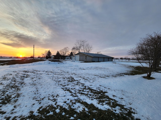 yard layered in snow with an outbuilding and a garage