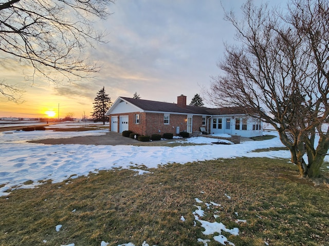 snow covered rear of property featuring a garage and a lawn