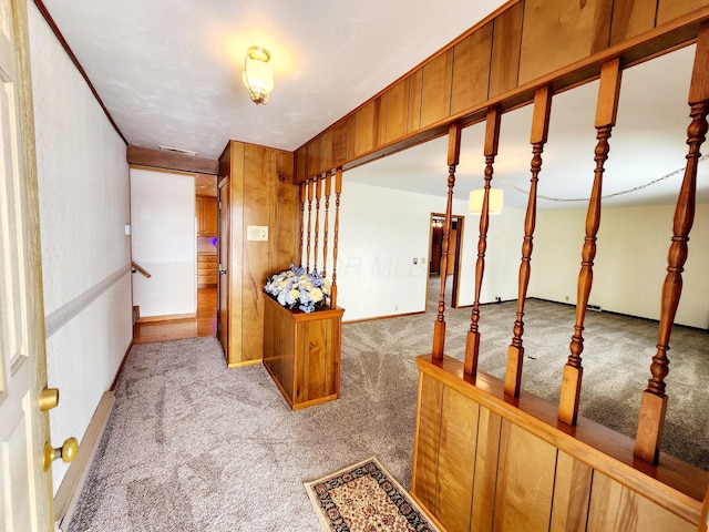 hall featuring light carpet and wood walls