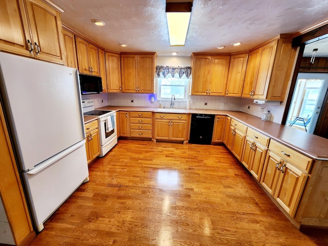 kitchen with sink, decorative backsplash, black appliances, and light hardwood / wood-style floors