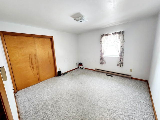 unfurnished bedroom featuring carpet flooring, baseboard heating, and a closet