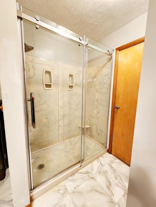 bathroom featuring a shower with door and a textured ceiling