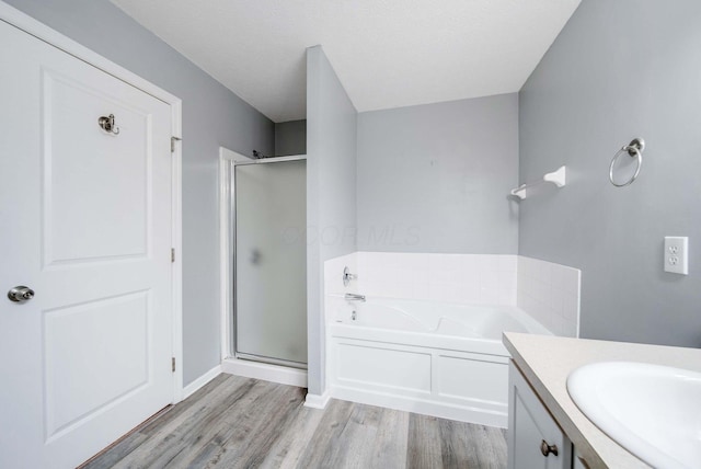 bathroom with vanity, separate shower and tub, hardwood / wood-style floors, and a textured ceiling