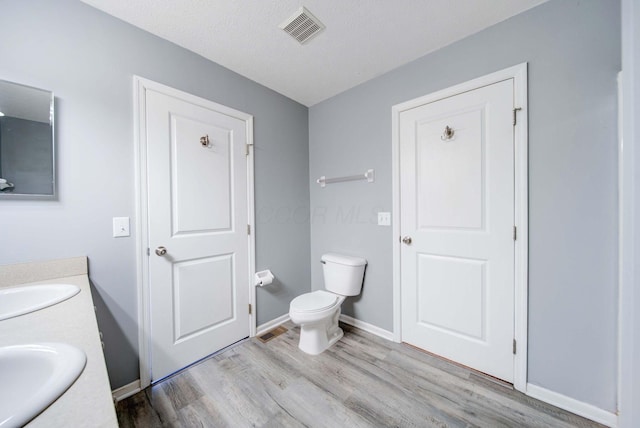 bathroom with vanity, hardwood / wood-style flooring, toilet, and a textured ceiling