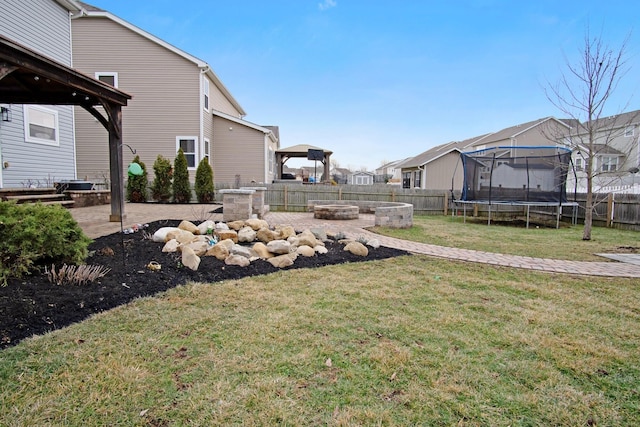 view of yard with a trampoline, a gazebo, a fire pit, and a patio